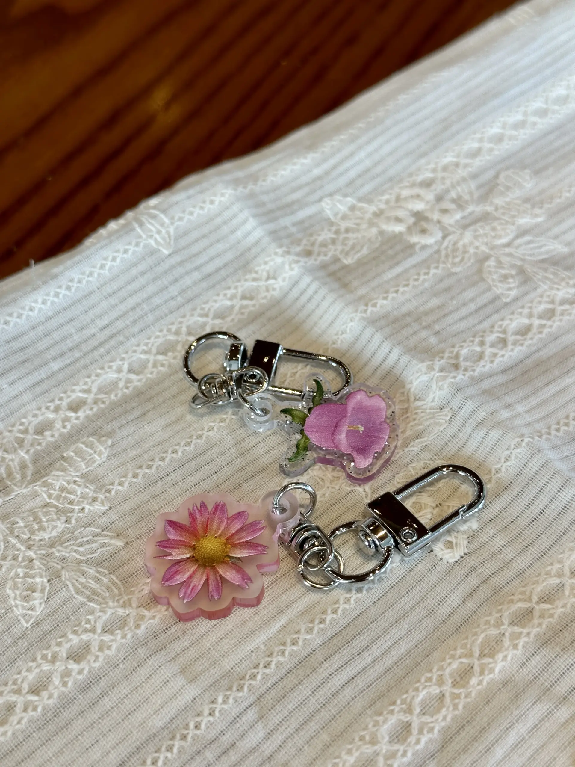 Flower acrylic keychains beside a grid notebook and a green pouch