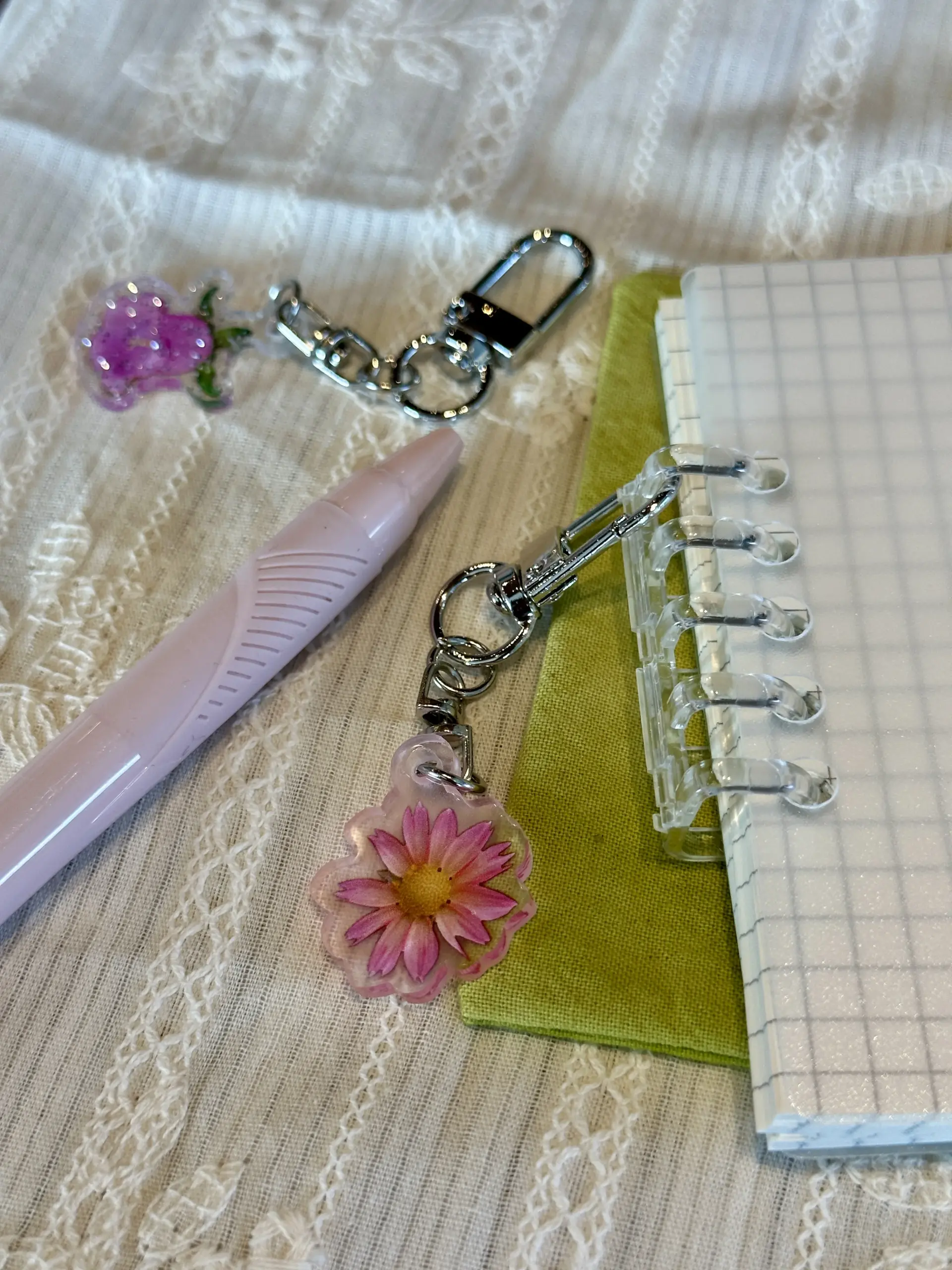 Close-up of a glitter bellflower keychain and a pink daisy keychain
